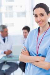 Nurse crossing arms with her colleagues behind