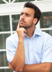 Thoughtful young businessman in front of his office