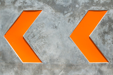 Orange arrow sign on cement background