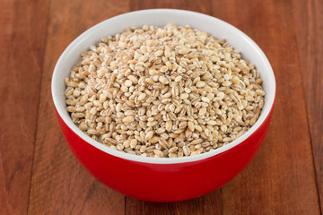 pearl barley in red bowl on dark background