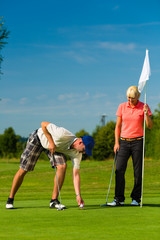 Obraz premium Young sportive couple playing golf on a course