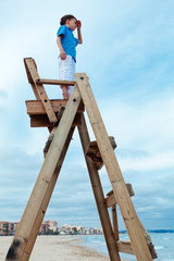 Boy sitting on lifeguard chair