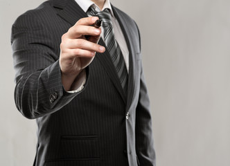 Trendy businessman writing with ballpoint on glass board