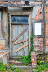 Old dilapidated door in masonry house front
