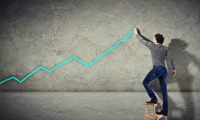 Young man drawing a graph on the wall