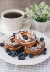 Cream puffs or choux pastry rings with blueberries on the plate