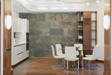 Dining room with round glass table, white chairs and cupboar