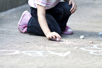 Back to school concept girl drawing with chalk on the schoolyard