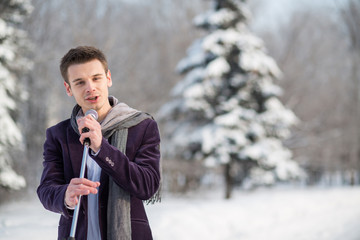 The singer in suit sing holding microphone in winter