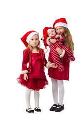 girls stand in Santa Claus hats, one holding baby boy
