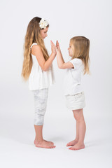 Two girls dressed in white playing slapping each others hands