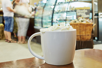 Cup of coffee with cream on table in cafeteria