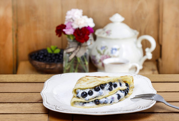 Pancakes with blueberries on wooden table.