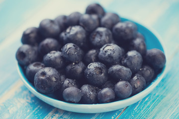 Fresh blueberries in a saucer on wooden boards, studio shot