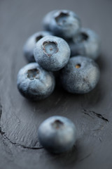 Vertical shot of blueberries on black wooden background, macro
