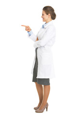 Full length portrait of doctor woman pointing on copy space