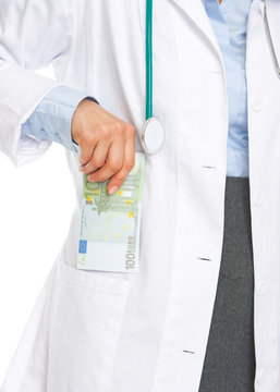 Closeup on doctor woman putting stack of euros in pocket