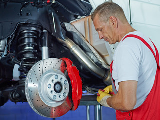 Car mechanic in a garage looking at the brake