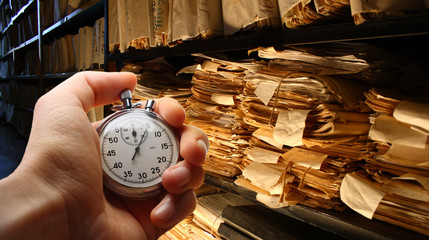 Fototapeta Hand with stopwatch, paper documents stacked in archive obraz