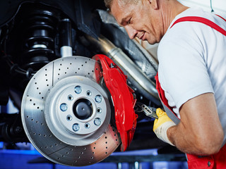 Car mechanic in a garage repairs a brake