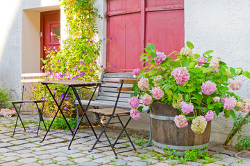 Romantischer Hauseingang mit Gartenmöbel und Pflanzen