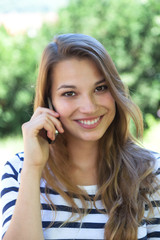 Beautiful young woman smiling on the phone in a park