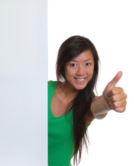 Asian woman showing thumb behind a signboard