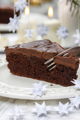 Piece of chocolate cake in white christmas table setting