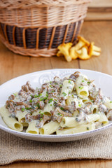 Macaroni with mushrooms on wooden rustic table. Autumn setting