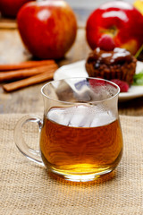 Glass of hot steaming tea on hessian napkin. Red apples