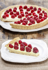 Piece of raspberry tart on wooden table. Summer garden party set