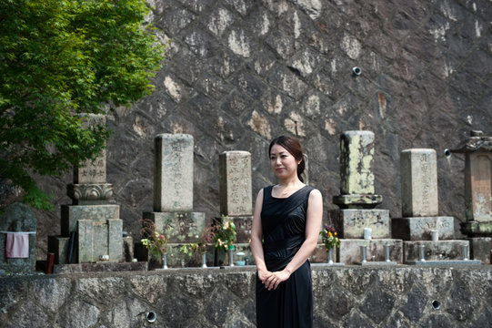 墓地で参拝する黒い服の女性