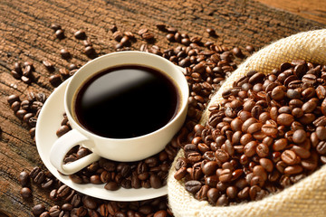 Coffee cup and coffee beans on old wooden background