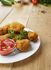 Fried chicken nuggets on the plate on the wooden table