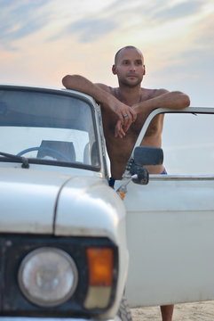 man near the car on a sandy beach