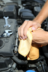 Obraz premium Motor mechanic cleaning his greasy hands after servicing car