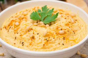 Hummus with pine nuts in a bowl, close-up, selective focus