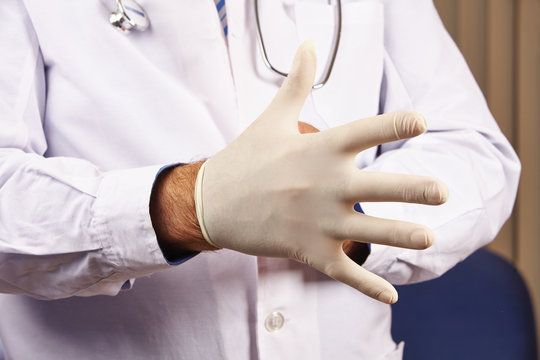 Arzt zieht sich Handschuh an