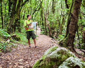 Naklejka na ściany i meble Hiker with map in forest