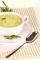 Nourishing soup in pink pan on wooden table close-up