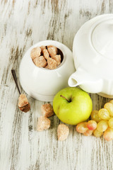 Unrefined sugar in white sugar bowl on wooden background