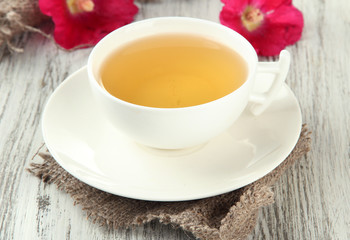 Cup of tea and pink mallow flowers on wooden background
