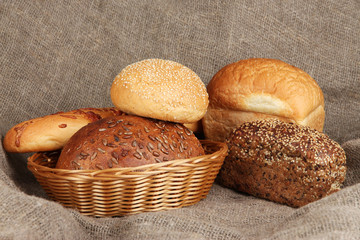 Baked bread in wicker basket on burlap background