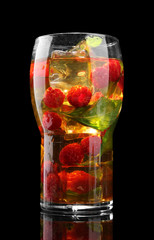 Iced tea with raspberries and mint on black background