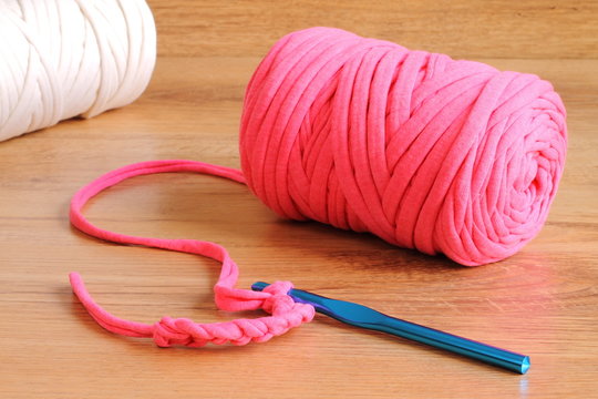 Pink zpagetti t-shirt yarn skein with a blue crochet hook