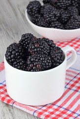 Sweet blackberries in cup on table close-up