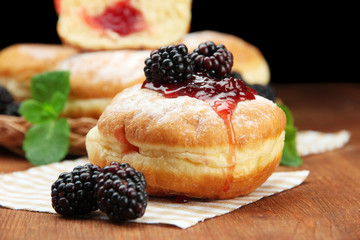 Tasty donuts with berries on wooden table
