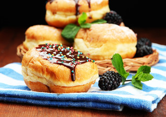 Tasty donuts with chocolate and berries on wooden table