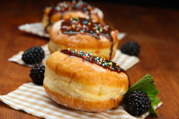 Tasty donuts with chocolate and berries on wooden table