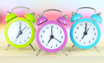 Colorful alarm clocks on table on light background